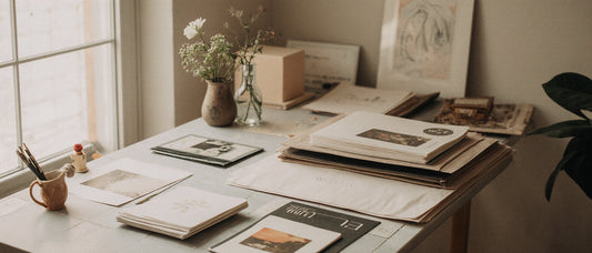 Organized and sunny artist studio desk with neatly stacked papers 