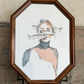 Woman with fish swimming in front of face in a wooden octagon frame against a stone wall. Artist: Joëlle Diane