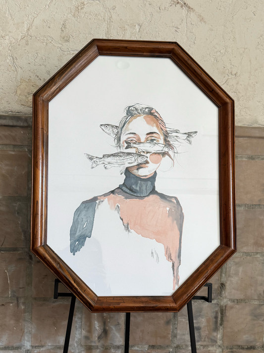 Woman with fish swimming in front of face in a wooden octagon frame against a stone wall. Artist: Joëlle Diane