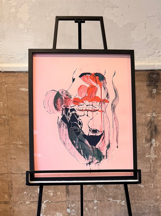 Artistic depiction of a person on a pink background displayed on an easel against a textured wall. Ambigram portrait. Artwork by Joëlle Diane of Monochrome Canvas.