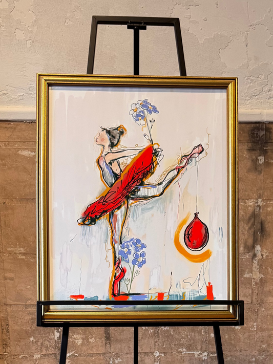 Artistic painting of a dancer with a deflated red balloon in a gold frame on an easel against a textured wall. Artwork by Joëlle Diane of Monochrome Canvas.