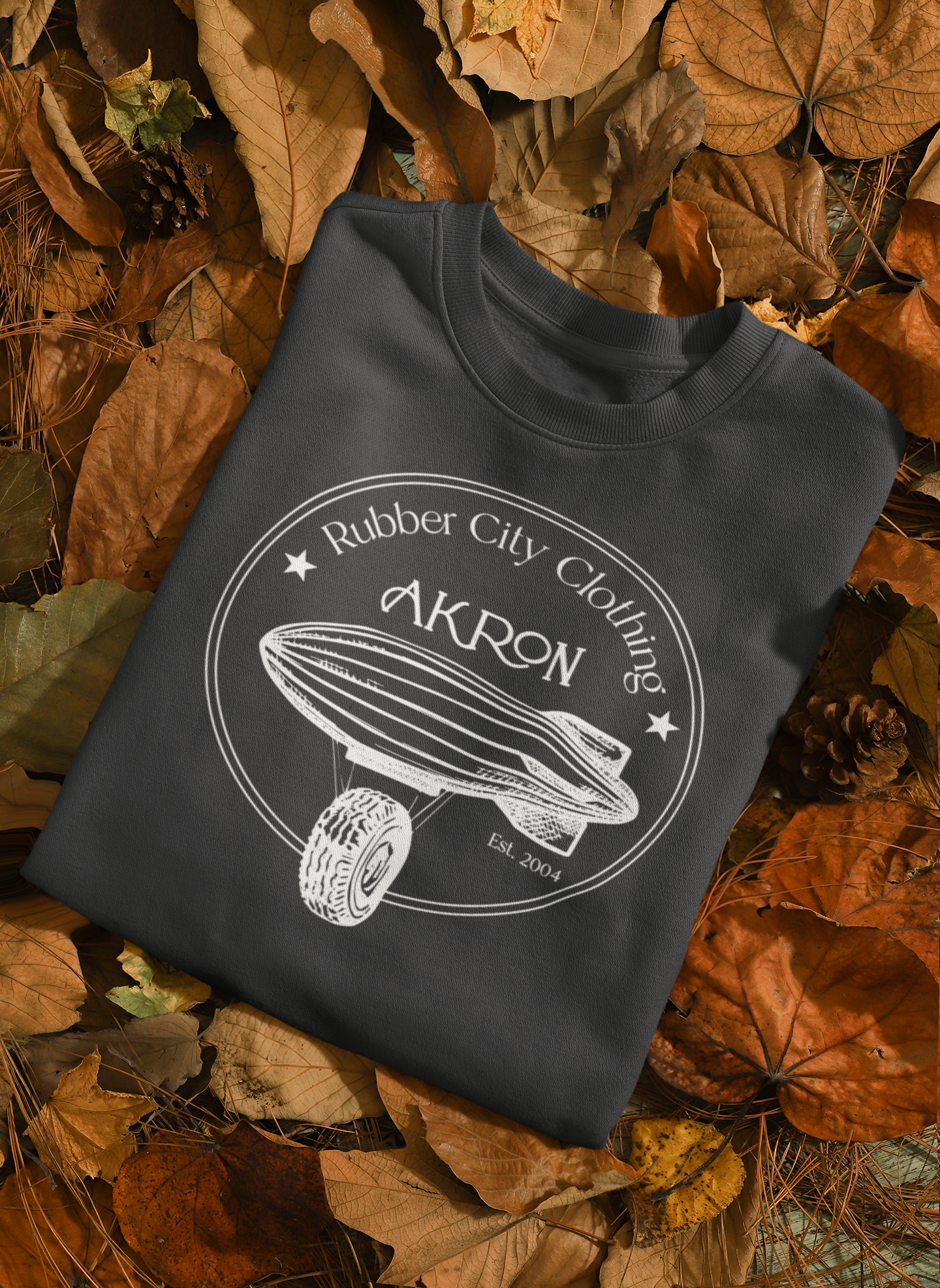mockup-featuring-a-sweatshirt-placed-on-autumn-leaves. vintage inspired Rubber City Clothing Design of blimp and tire - Designed by Joëlle Diane of Monochrome Canvas